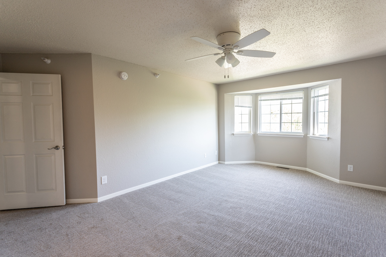 an empty living room with a ceiling fan and a window