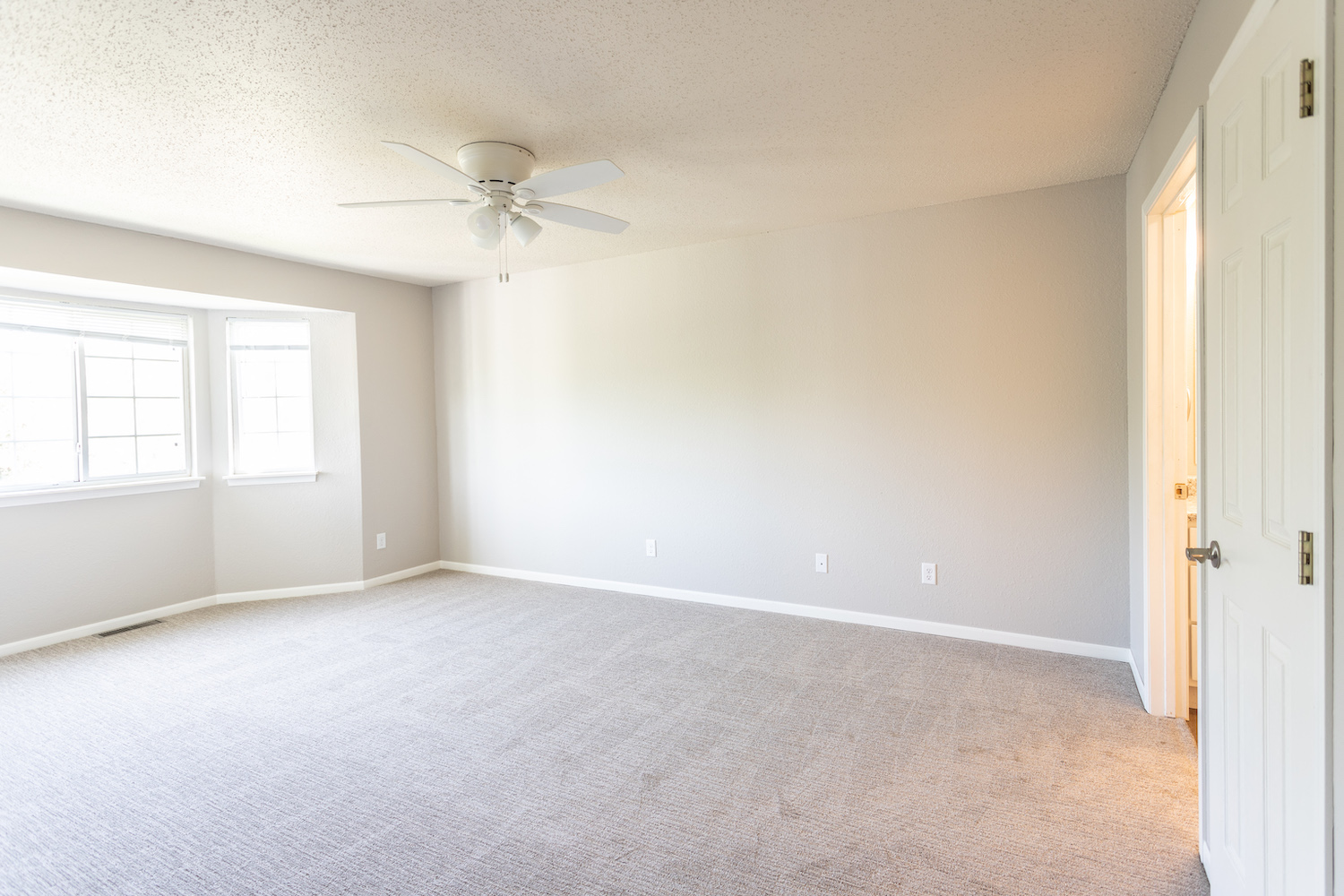 an empty room with a ceiling fan and a window