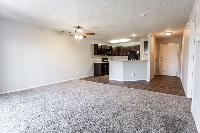 an empty living room and kitchen with a ceiling fan