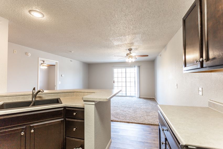 an empty kitchen and living room with a ceiling fan