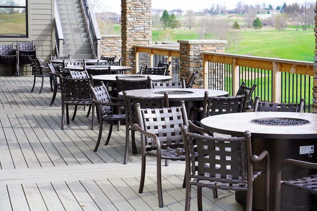 a patio with tables and chairs on a deck