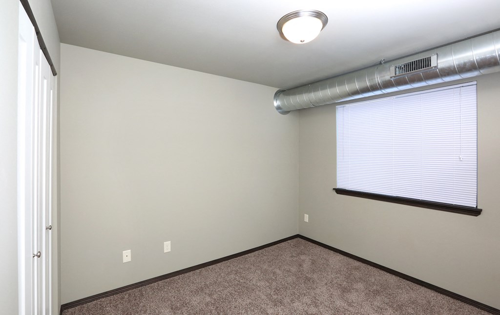 an empty room with a large window and a carpeted floor