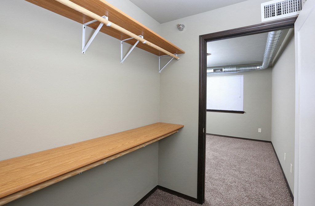 a walk in closet with a wooden bench and a mirror