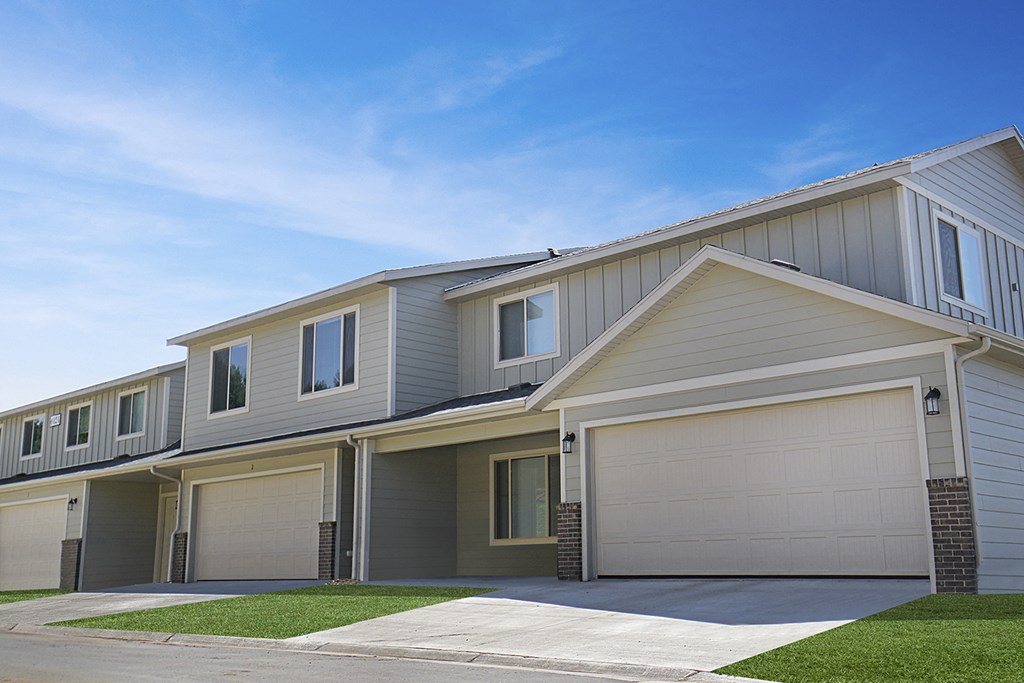 a row of houses with garage doors and a sidewalk