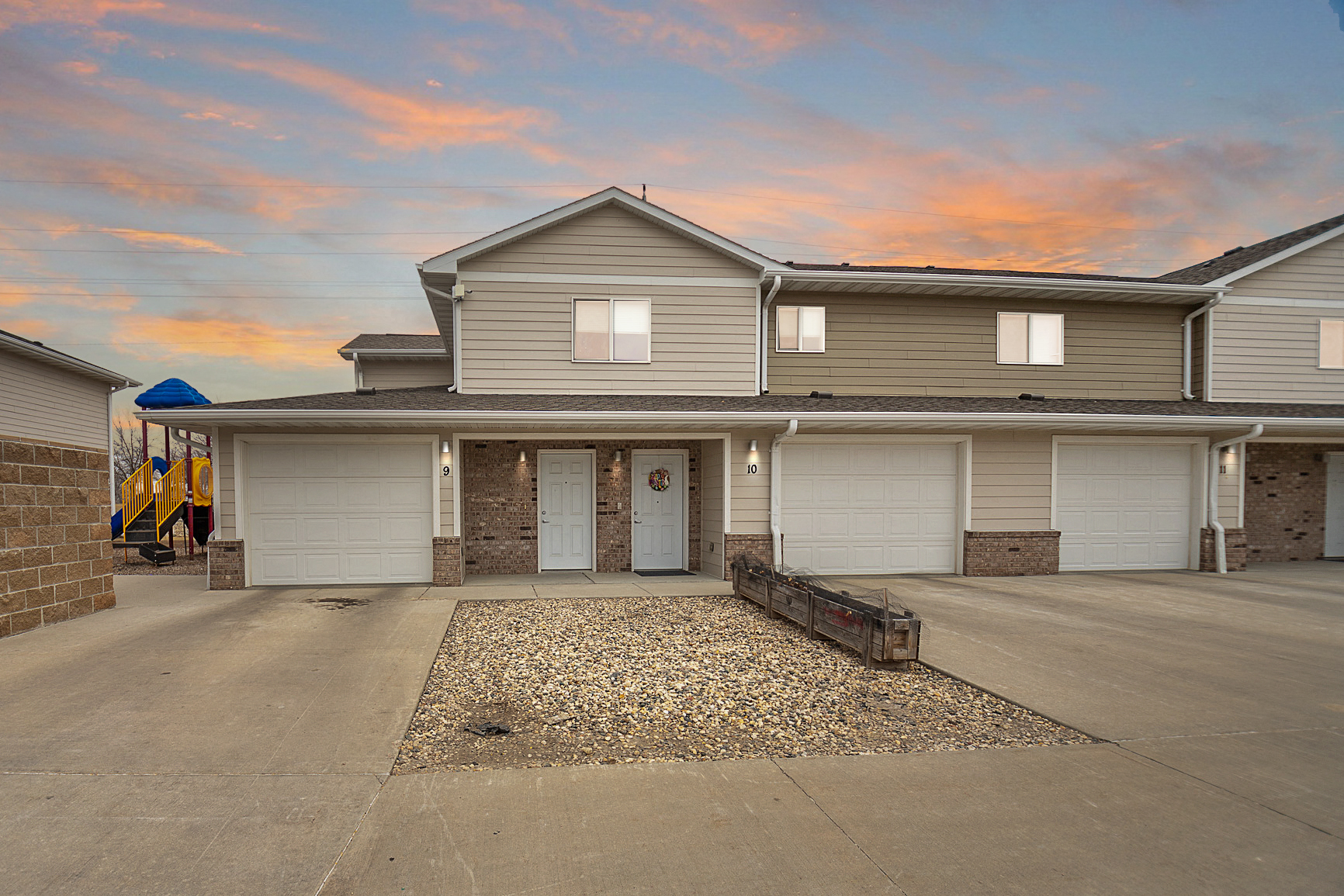 a house with white garage doors with a sunset in the background
