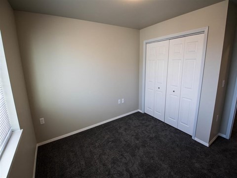 a bedroom with a carpeted floor and two closets