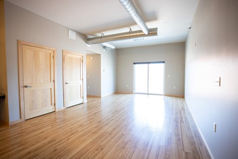 an empty living room with wood floors and white walls