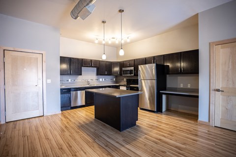 an empty kitchen with black and stainless steel appliances and wooden floors
