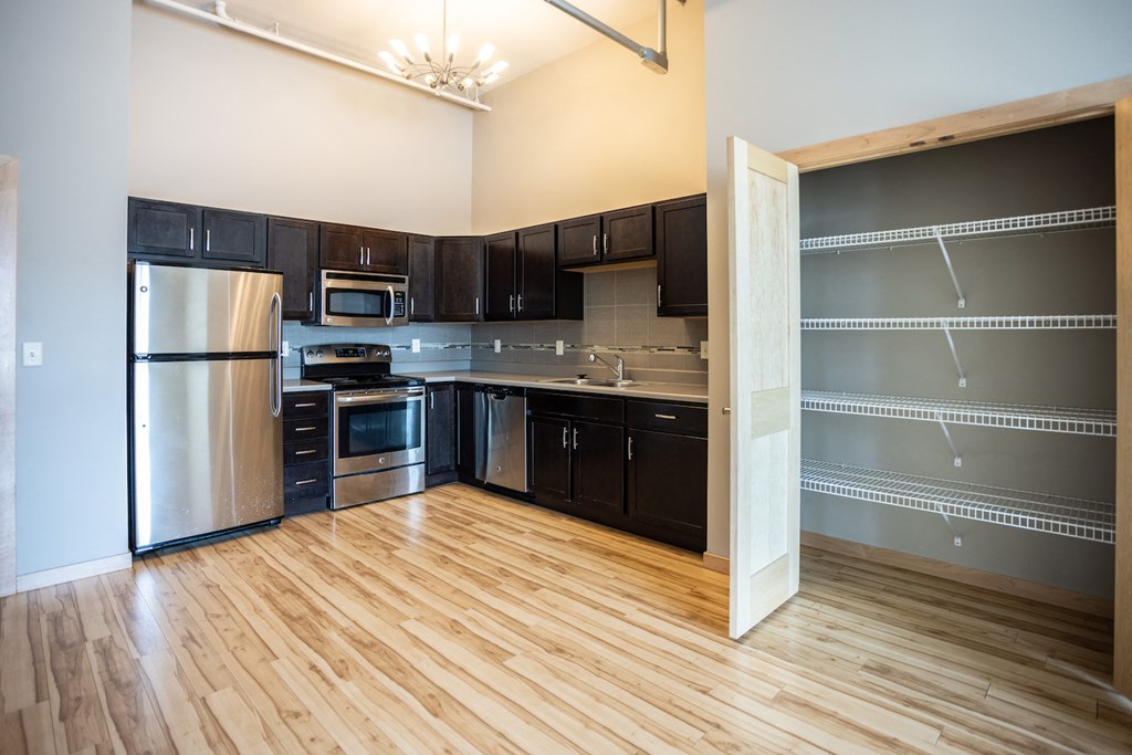 an empty kitchen with black cabinets and stainless steel appliances