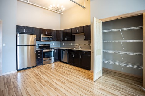 an empty kitchen with black cabinets and stainless steel appliances