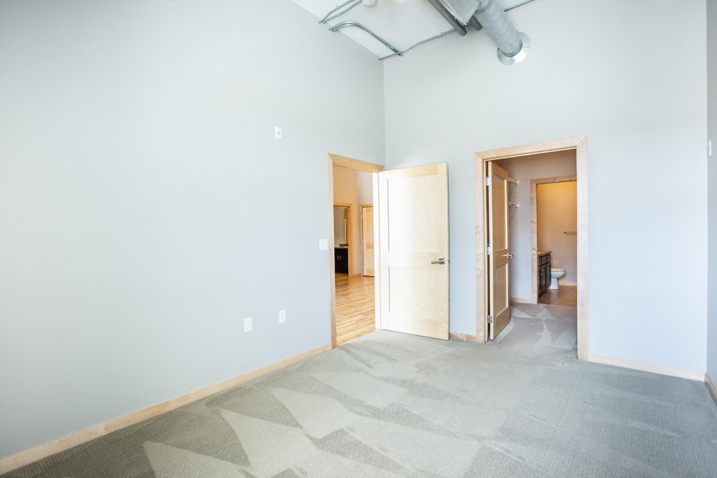 an empty room with a blue wall and a door to a bathroom