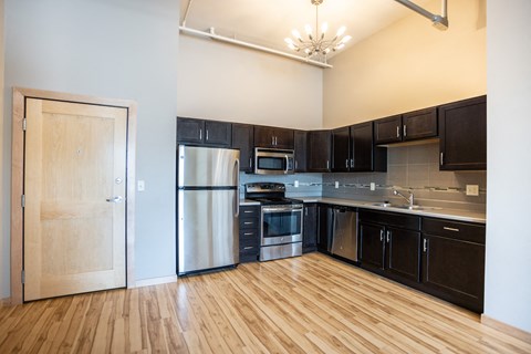 a kitchen with black cabinets and stainless steel appliances and a wooden floor