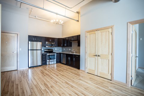 an empty living room and kitchen with wood flooring and black and white