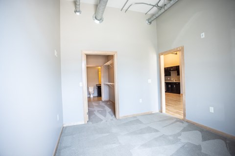 a room with white walls and a door to a bathroom and a doorway to a