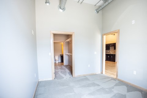 an empty room with a door to a bathroom and a kitchen
