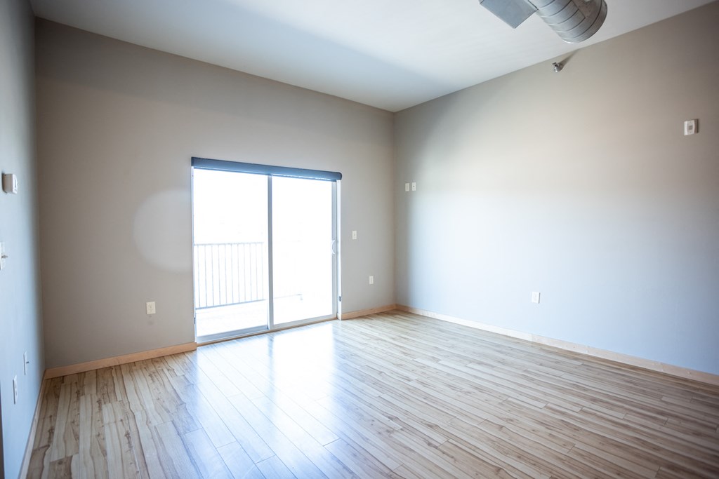 an empty living room with wood floors and a sliding glass door