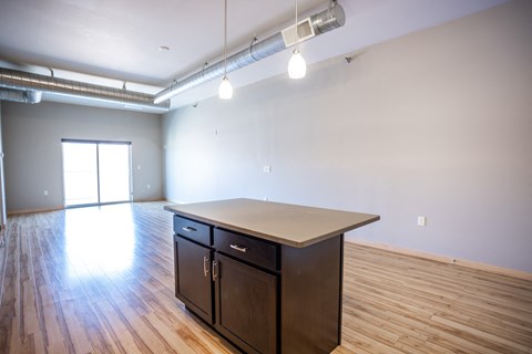 an empty living room with wood floors and an island in the middle