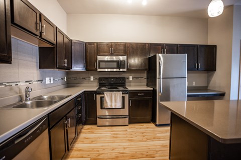 an empty kitchen with stainless steel appliances and wooden floors