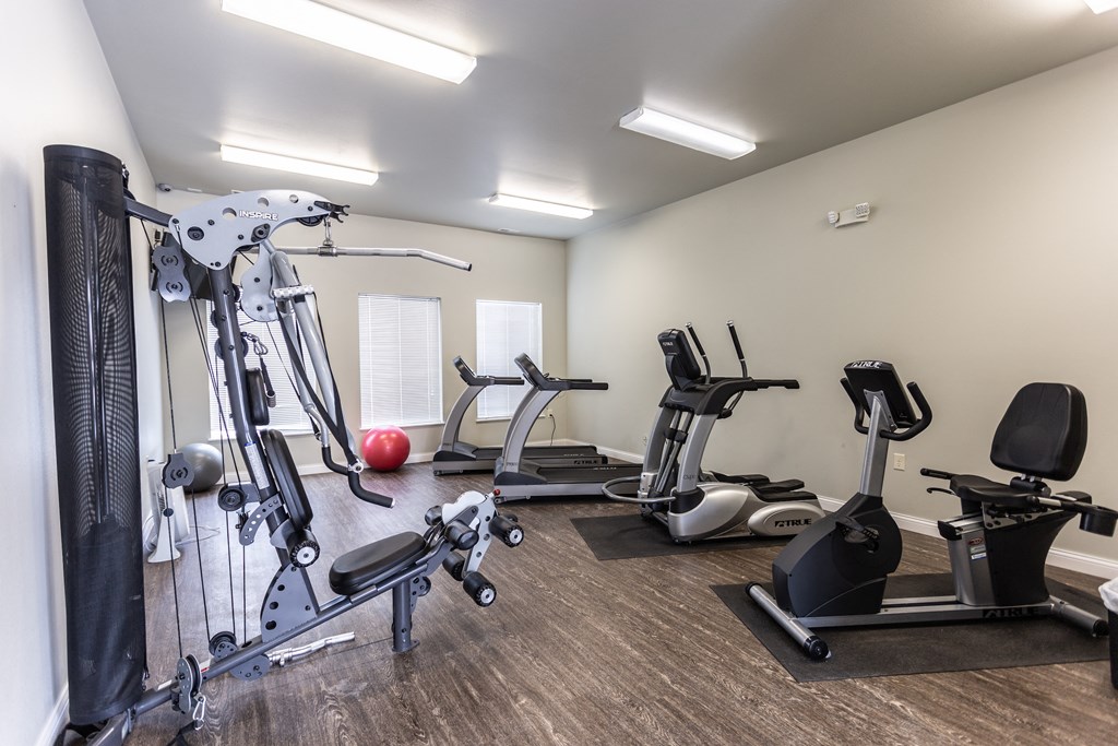 a gym with cardio machines and other exercise equipment on a wooden floor