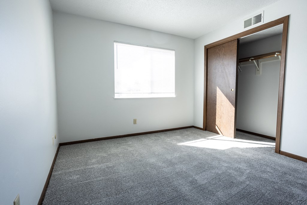 an empty room with a closet and a window