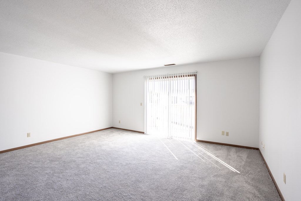 an empty living room with white walls and a sliding glass door