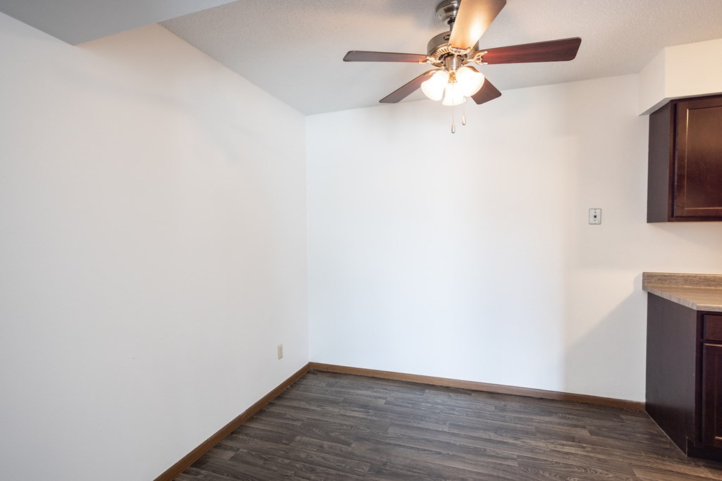 an empty living room with a ceiling fan