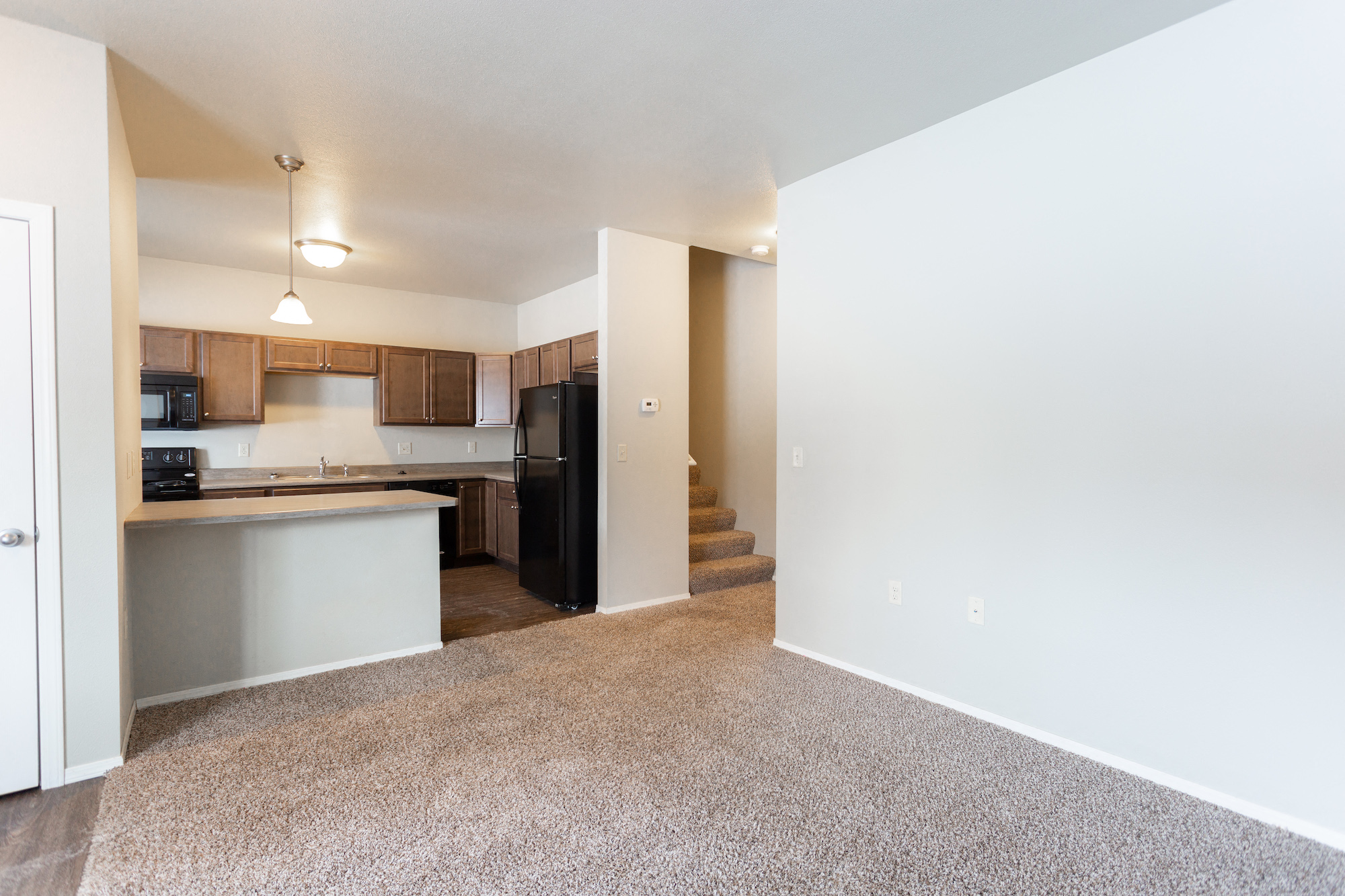 an empty apartment with a kitchen and a carpeted floor