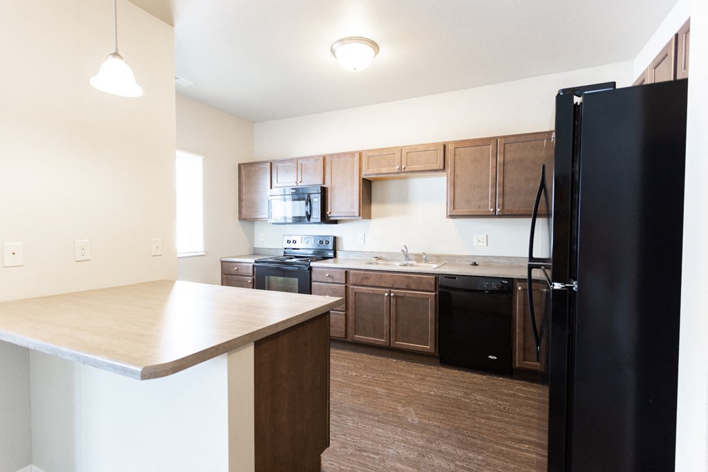 an empty kitchen with a counter top and a black refrigerator