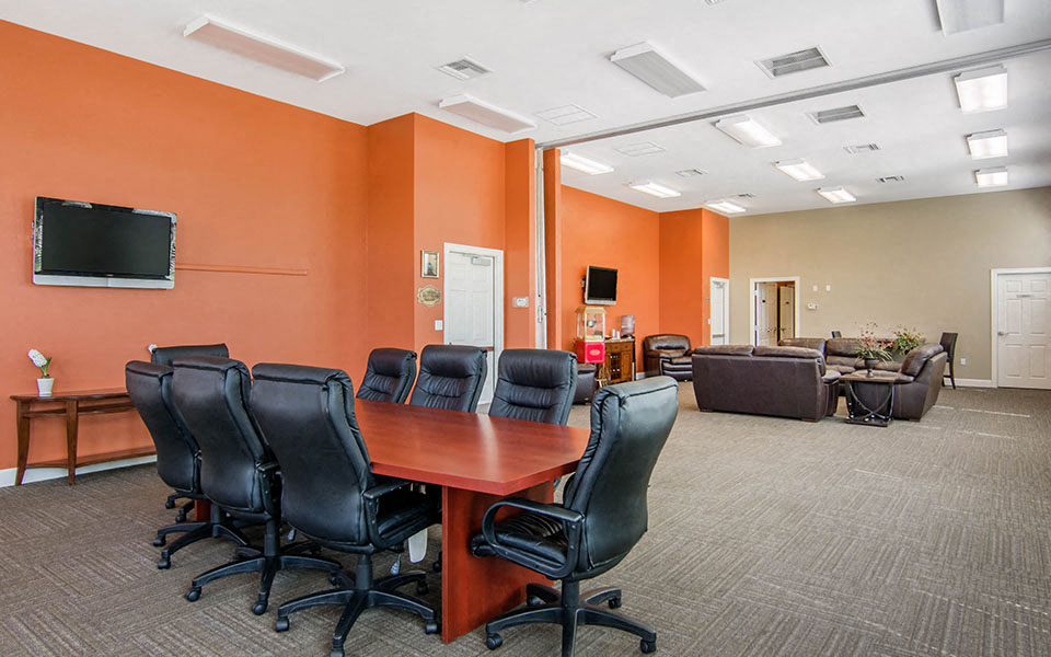 a conference room with a table and chairs and a television