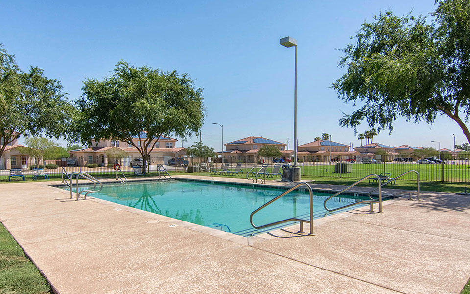 a swimming pool with a fence and trees around it