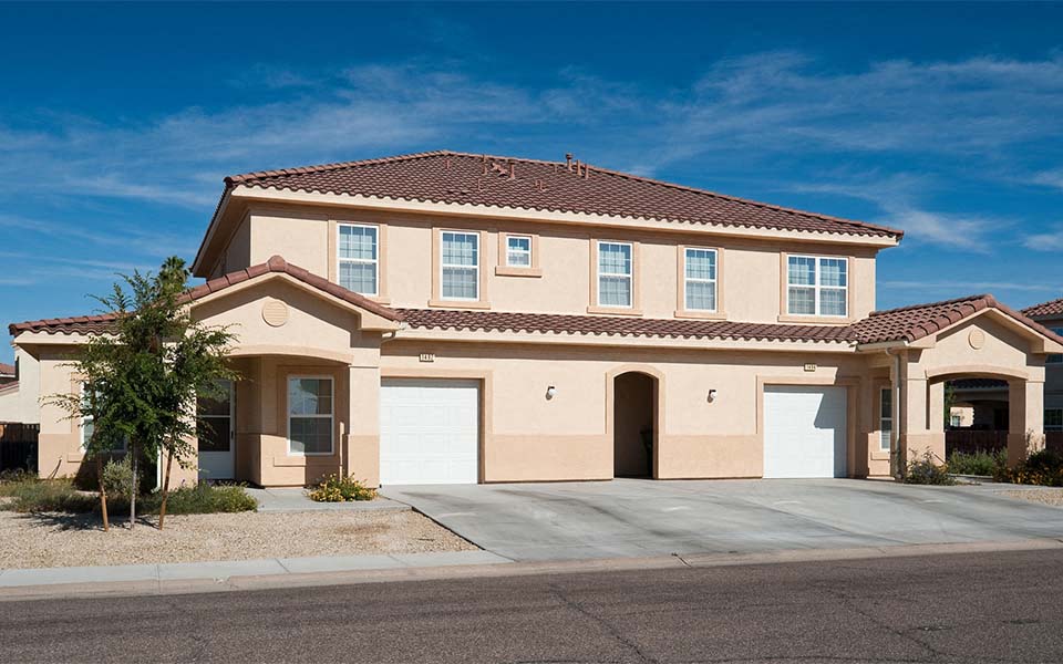 a beige house with two garage doors