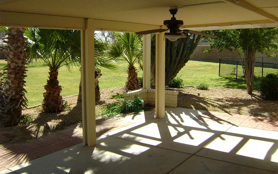 a porch with palm trees and a ceiling fan