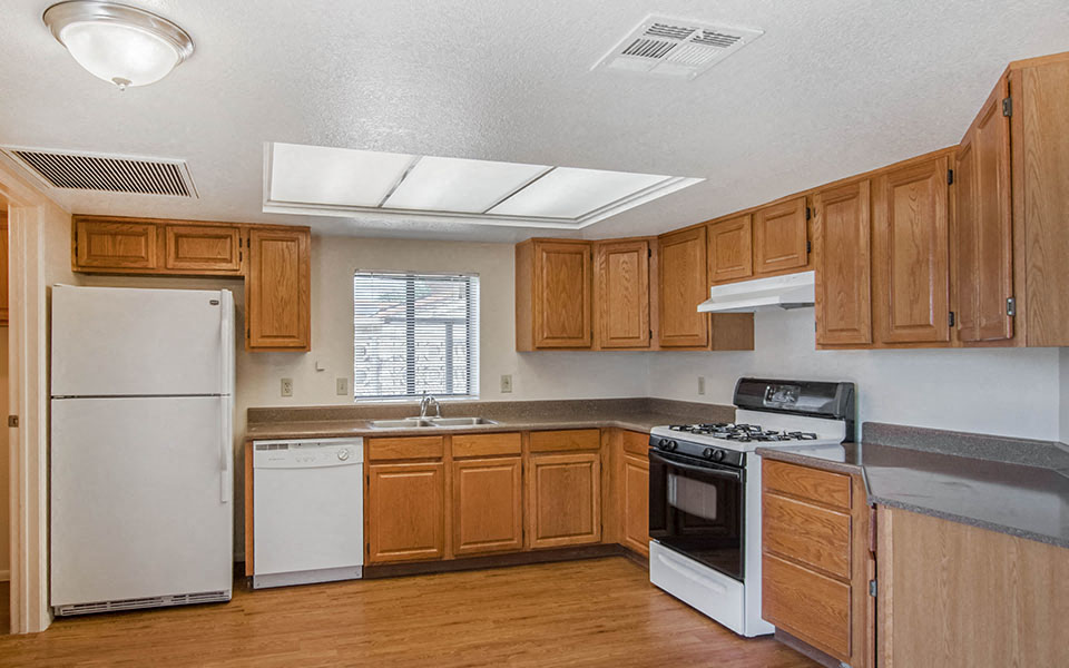 an empty kitchen with wooden cabinets and white appliances