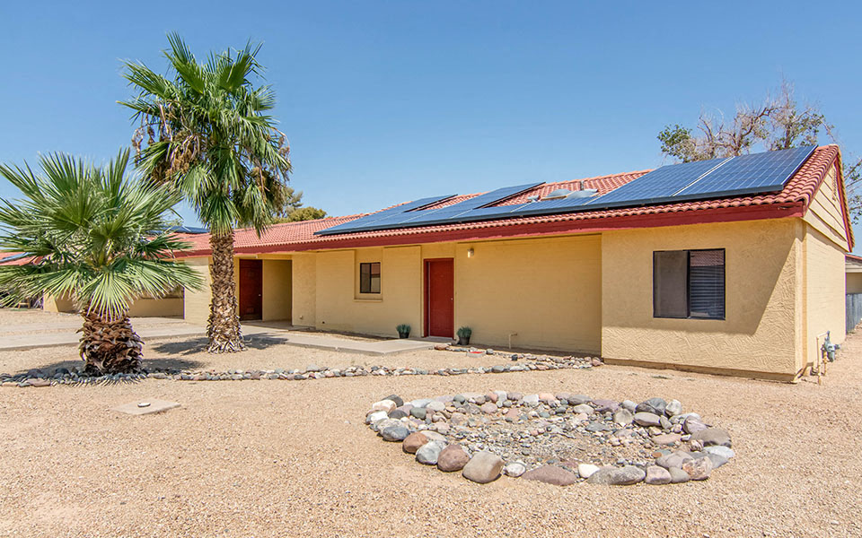 a house with solar panels on the roof and a palm tree