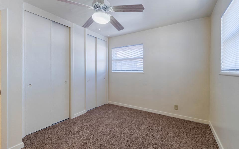 an empty room with a ceiling fan and white closets