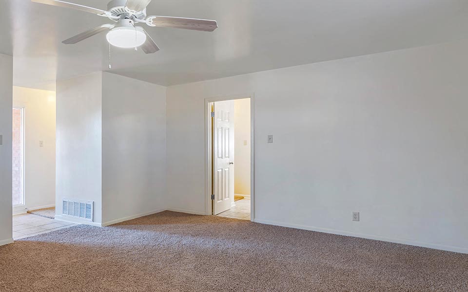 an empty living room with a ceiling fan