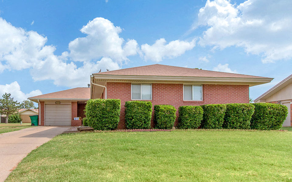 a brick house with hedges in front of it