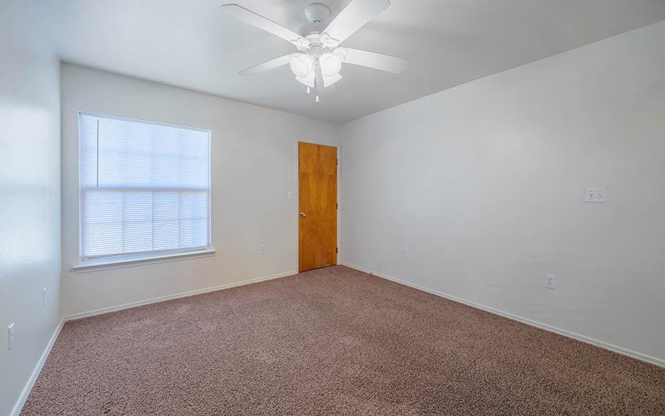 an empty room with a ceiling fan and a window