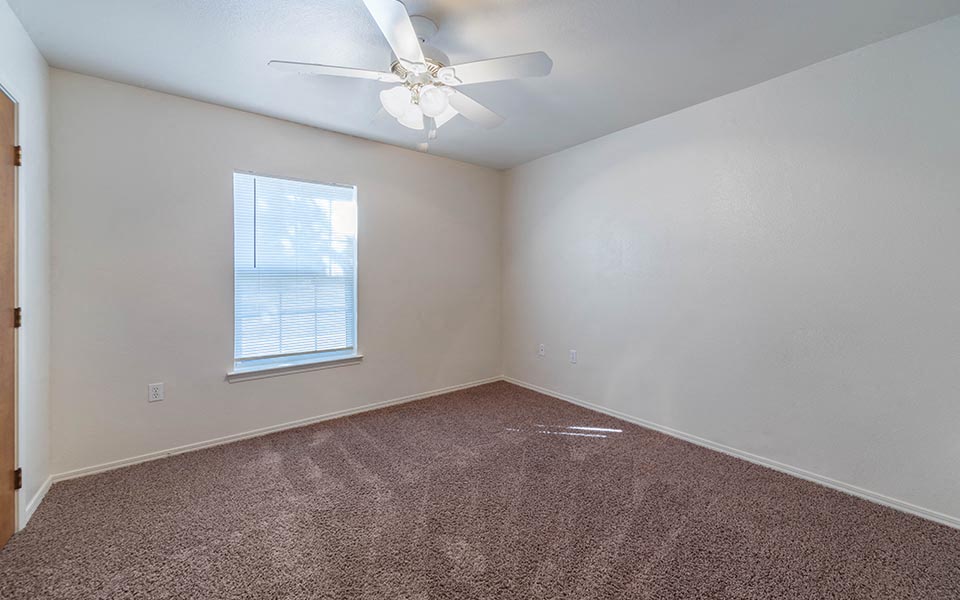 an empty room with a ceiling fan and a window