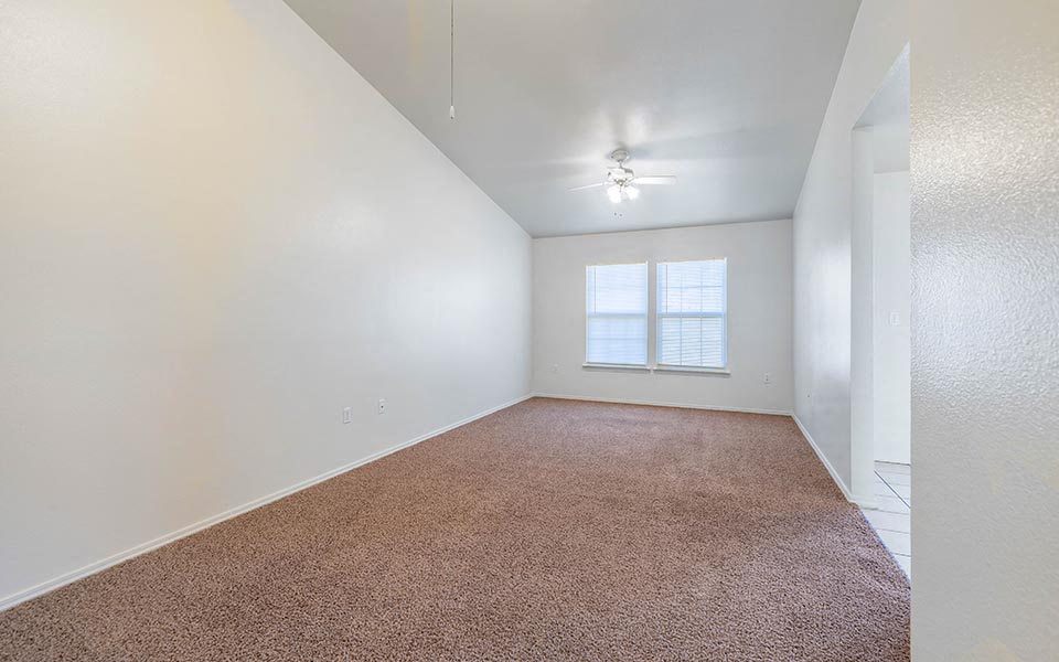 an empty living room with a window and carpet