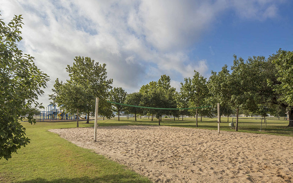 a volleyball court in a park with trees