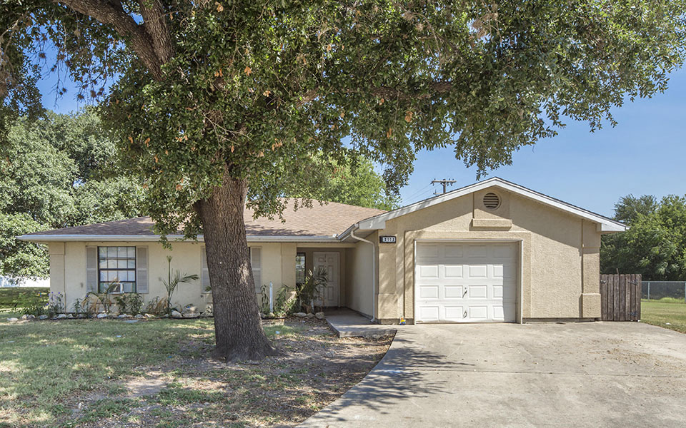 a tan house with a tree in front of it