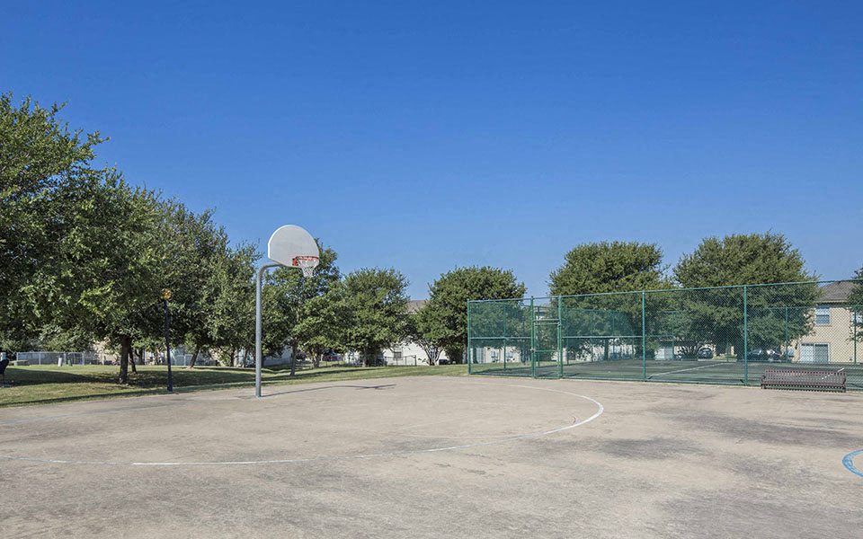 a basketball court in a park with trees