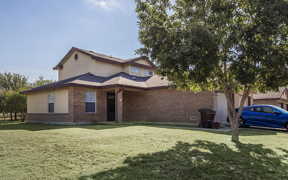 a house with a tree and a blue car in the yard