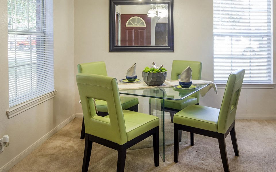 a dining room with a glass table and green chairs