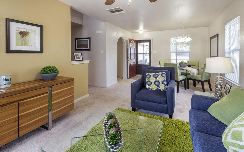 a living room with blue chairs and a green rug
