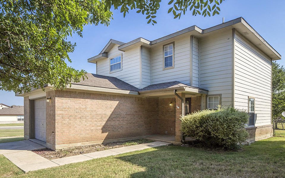 a white house with a brick wall and a garage