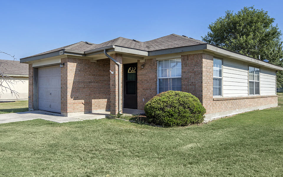a small brick house with a yard and a garage
