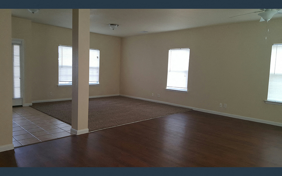 an empty living room with wood floors and windows
