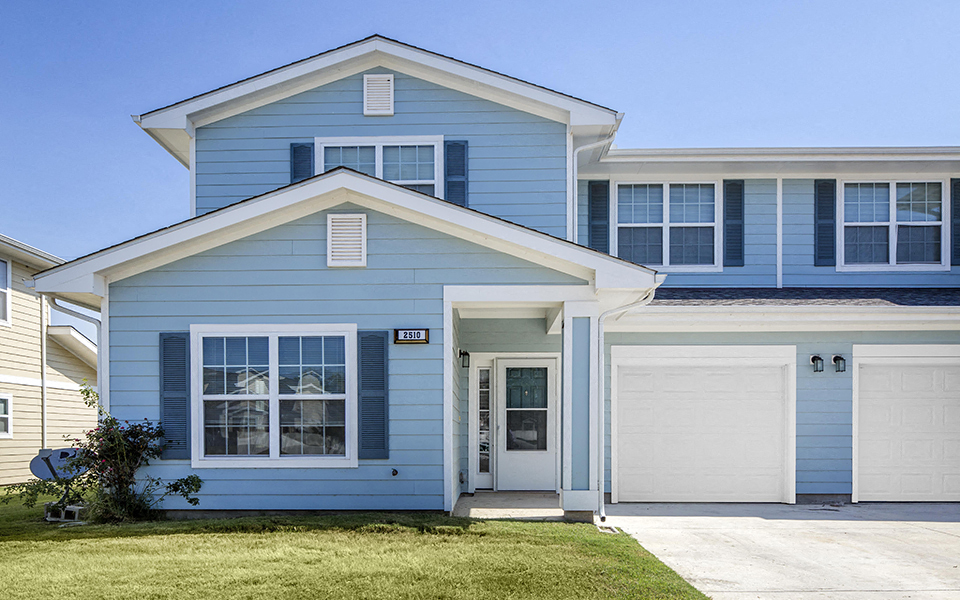 a blue house with a white door and a lawn